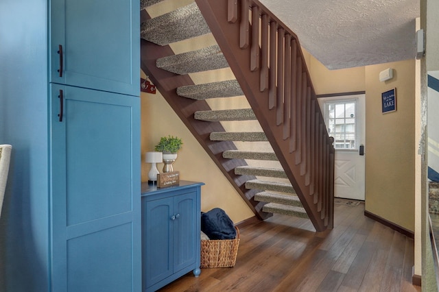 stairway with wood-type flooring and a textured ceiling