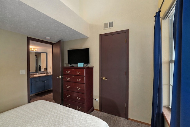 carpeted bedroom with a textured ceiling and ensuite bathroom