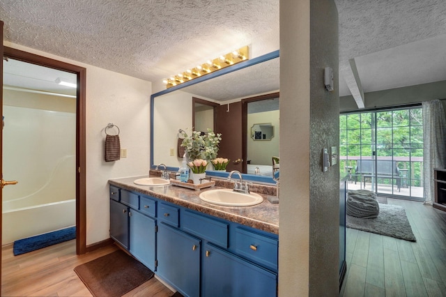 bathroom featuring wood-type flooring, vanity, and a textured ceiling