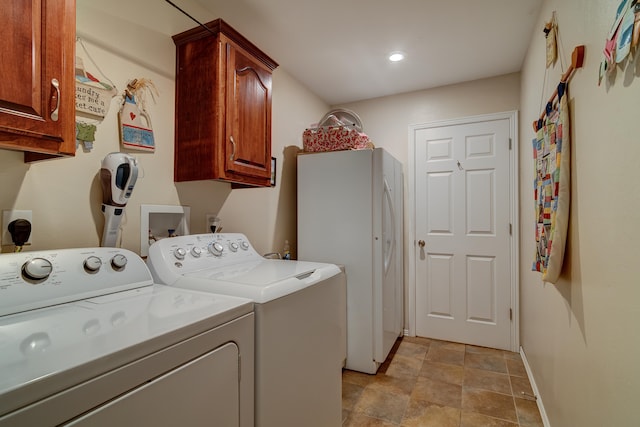 clothes washing area with washing machine and clothes dryer and cabinets