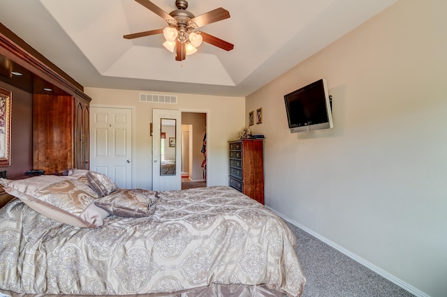 carpeted bedroom with ceiling fan and a raised ceiling