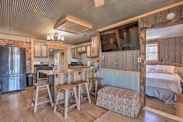 3142 Fishin Hole Rd, Flemington, MO 65650 - kitchen featuring wooden walls, a sink, a peninsula, light wood-style flooring, and appliances with stainless steel finishes