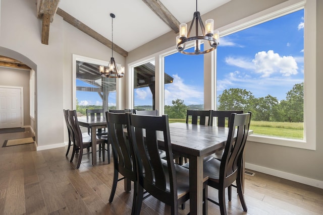 dining area featuring an inviting chandelier, dark hardwood / wood-style floors, and lofted ceiling with beams