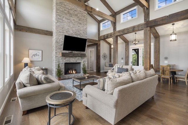 living room featuring a stone fireplace, beamed ceiling, dark hardwood / wood-style flooring, and high vaulted ceiling