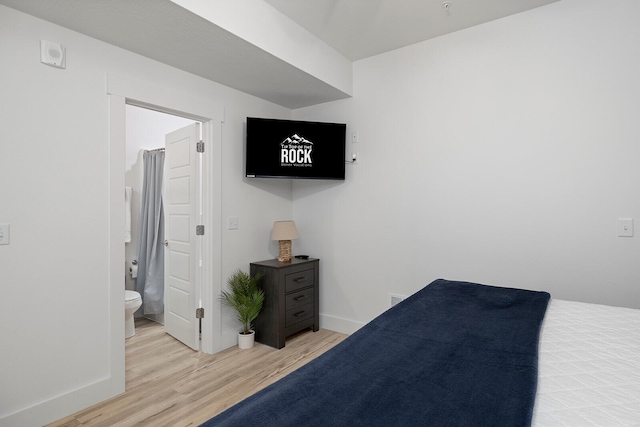 bedroom featuring ensuite bathroom and light hardwood / wood-style flooring