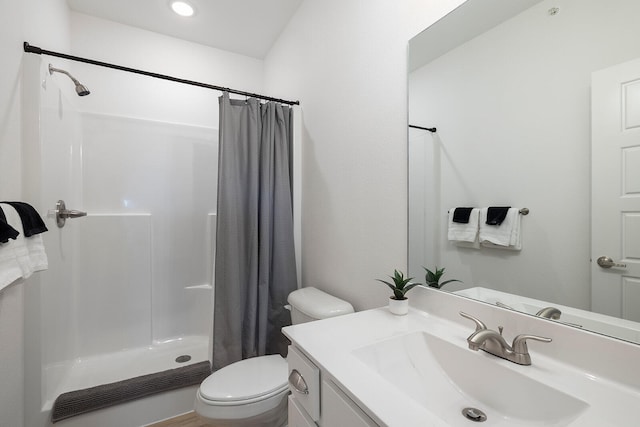 bathroom with walk in shower, vanity, and toilet