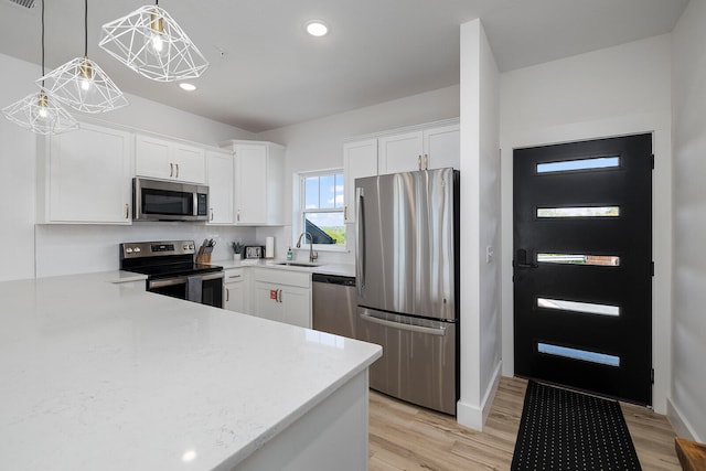 kitchen with stainless steel appliances, hanging light fixtures, white cabinetry, a chandelier, and light hardwood / wood-style flooring