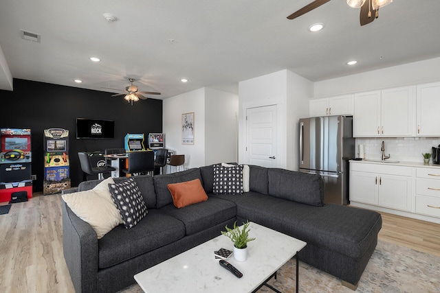 living room with sink, light hardwood / wood-style flooring, and ceiling fan