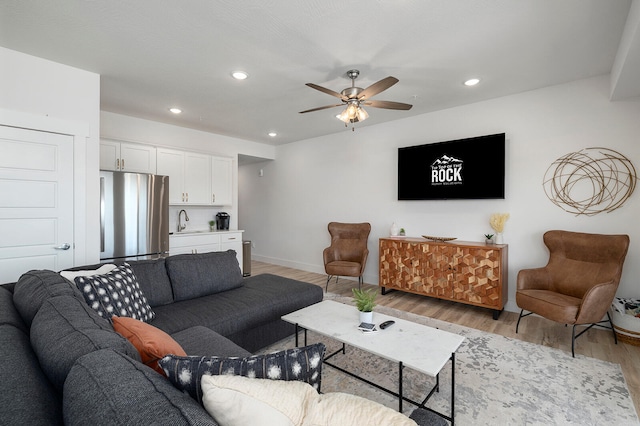 living room featuring ceiling fan, sink, and light hardwood / wood-style floors