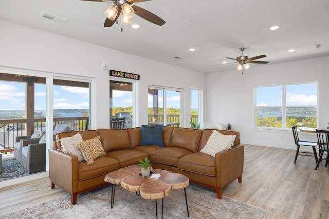 living room featuring ceiling fan, plenty of natural light, and light hardwood / wood-style flooring