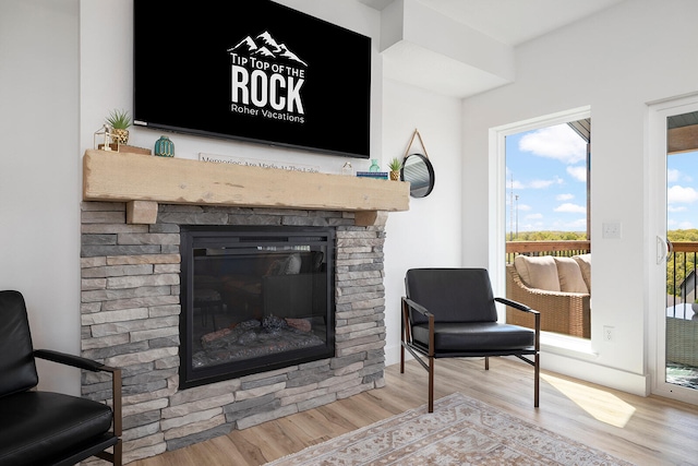 sitting room with a stone fireplace and light wood-type flooring