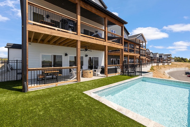 back of house with a balcony, a yard, and a fenced in pool