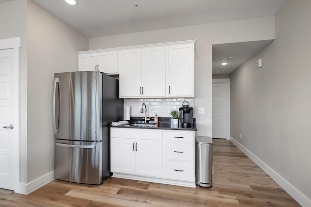 kitchen featuring stainless steel fridge, sink, light hardwood / wood-style floors, and white cabinets