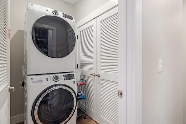 clothes washing area with hardwood / wood-style floors and stacked washer and dryer