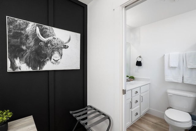 bathroom with wood-type flooring, vanity, and toilet