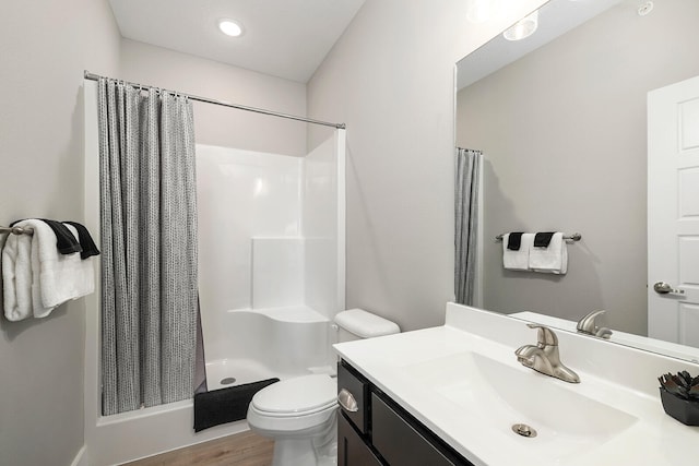 bathroom featuring curtained shower, hardwood / wood-style flooring, vanity, and toilet