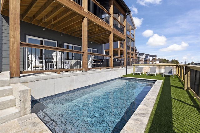 view of swimming pool featuring a wooden deck and a lawn