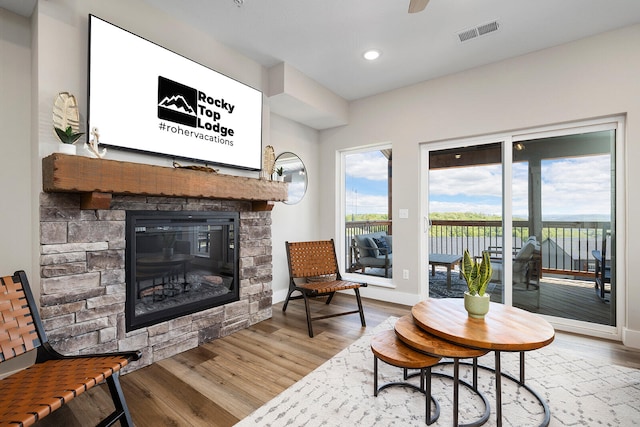 living area with light wood-type flooring and a stone fireplace