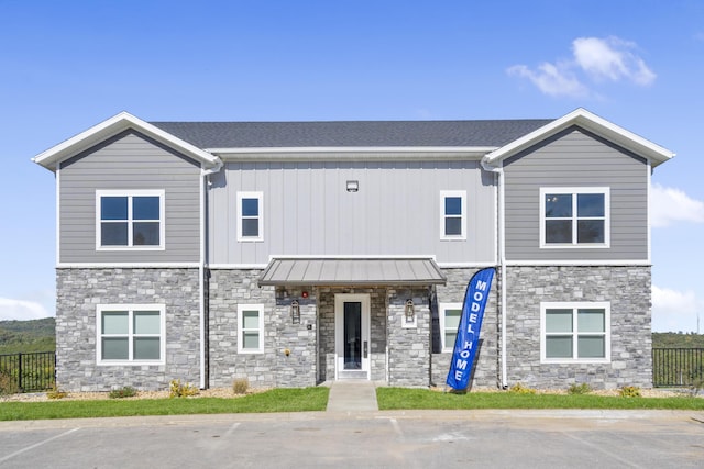 view of front of house with fence, stone siding, and board and batten siding