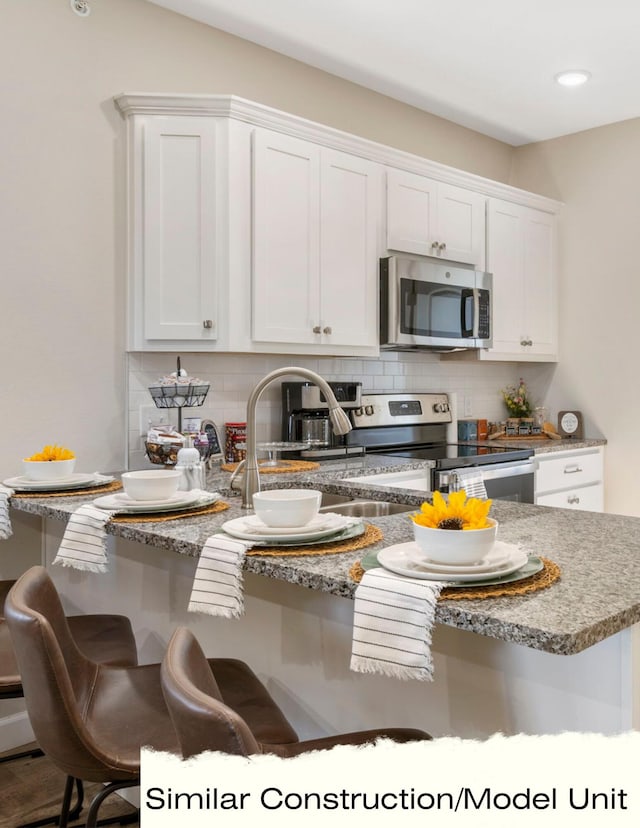 kitchen with white cabinetry, stainless steel appliances, and backsplash