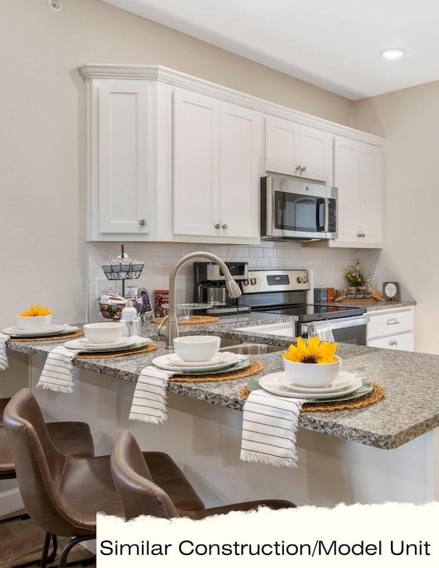 kitchen featuring decorative backsplash, stainless steel appliances, white cabinets, and a sink