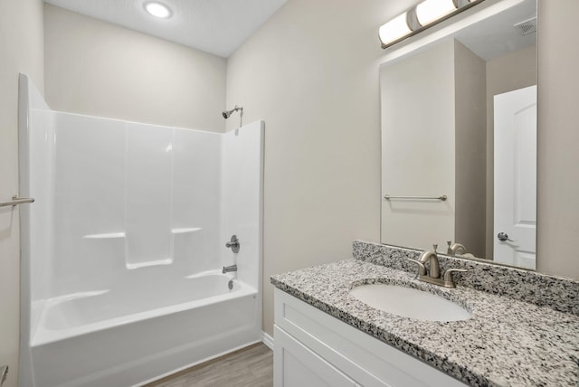 bathroom with shower / bathtub combination, vanity, wood finished floors, and visible vents