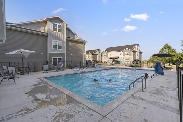 pool with fence, a patio area, and a residential view