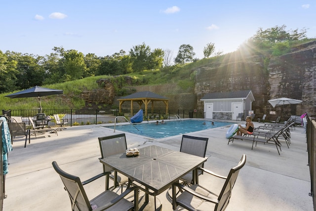 view of swimming pool featuring a gazebo, a patio, and an outbuilding