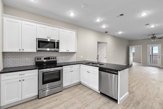 kitchen with visible vents, a sink, light wood-style floors, a peninsula, and appliances with stainless steel finishes