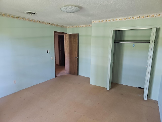 unfurnished bedroom with carpet, a textured ceiling, visible vents, and a closet