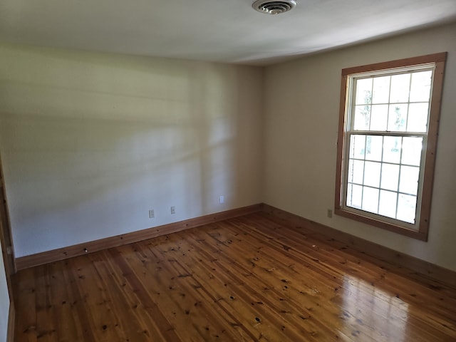 spare room with baseboards, visible vents, and wood-type flooring