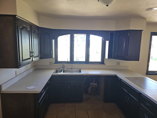 kitchen with plenty of natural light, a textured ceiling, tile patterned floors, and a sink