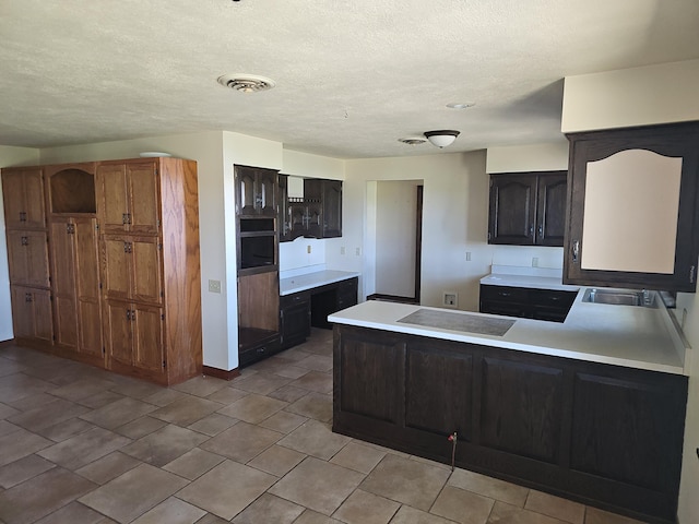 kitchen with oven, light countertops, visible vents, electric stovetop, and a peninsula