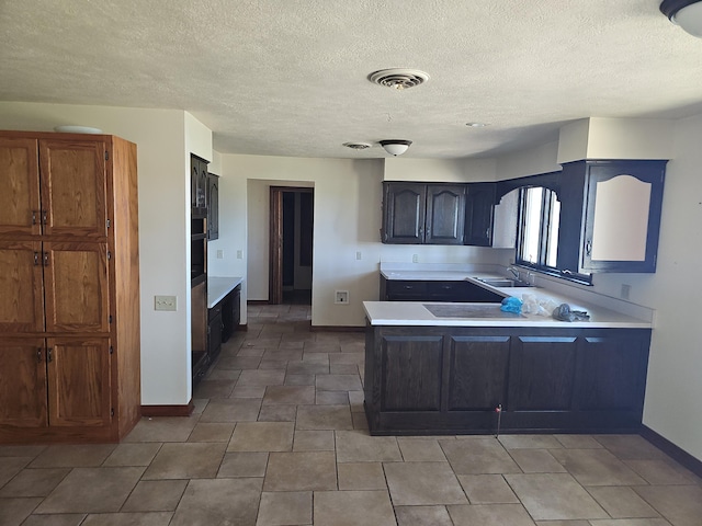 kitchen featuring baseboards, a peninsula, visible vents, and light countertops
