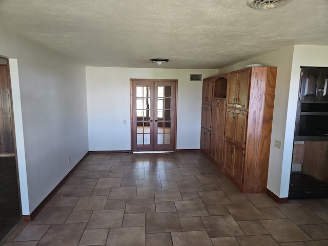 unfurnished room with baseboards, french doors, a textured ceiling, and visible vents