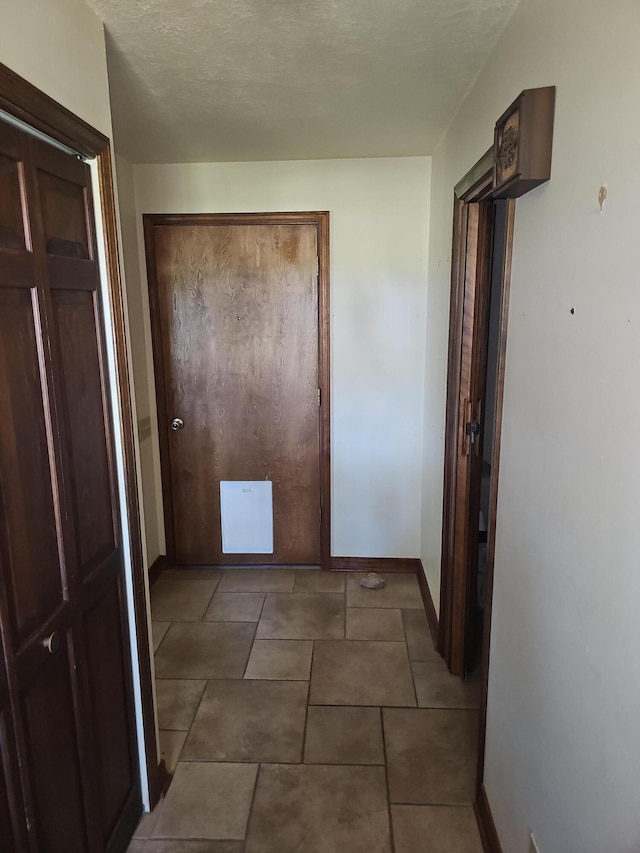 corridor with baseboards and a textured ceiling