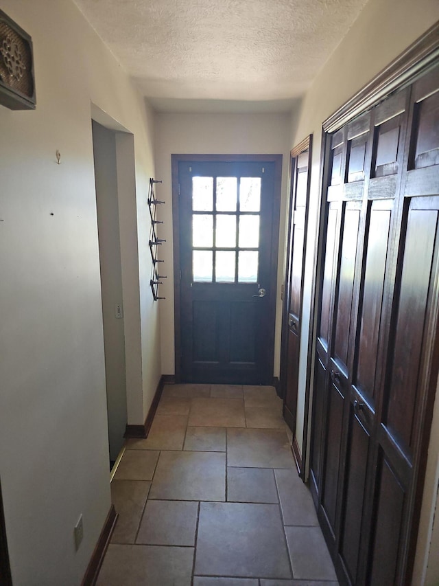 entryway with a textured ceiling, tile patterned flooring, and baseboards