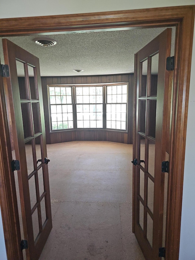 unfurnished room with french doors, visible vents, and a textured ceiling