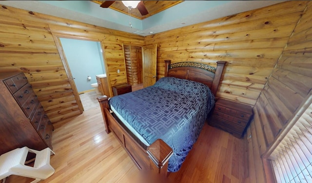 bedroom featuring a ceiling fan, light wood-style floors, visible vents, and ensuite bathroom