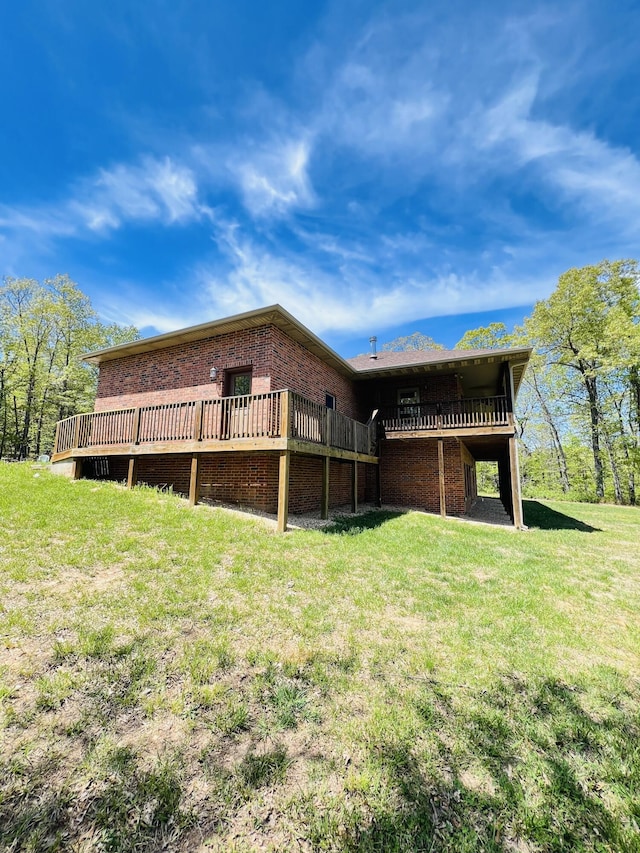 back of property with a wooden deck, brick siding, and a yard