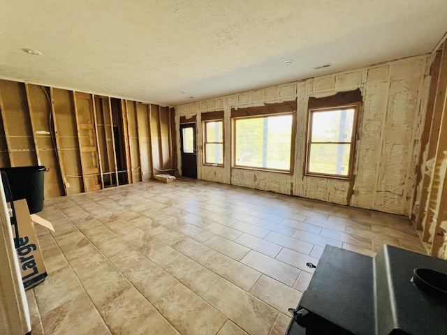 tiled empty room with a textured ceiling and visible vents