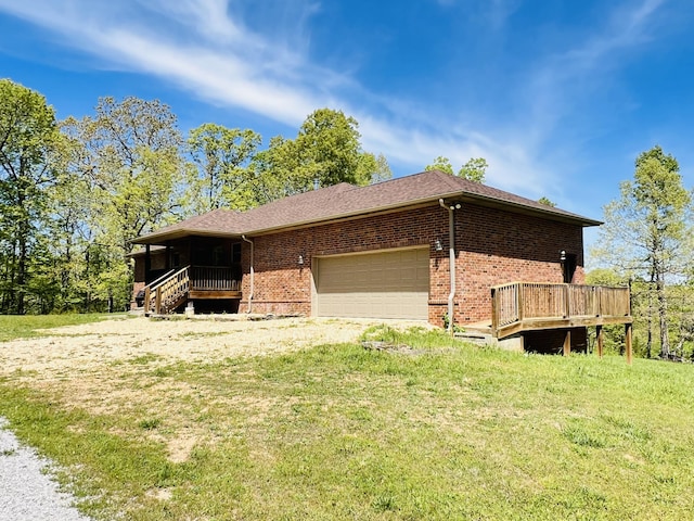 view of side of property featuring brick siding, a lawn, a garage, and driveway