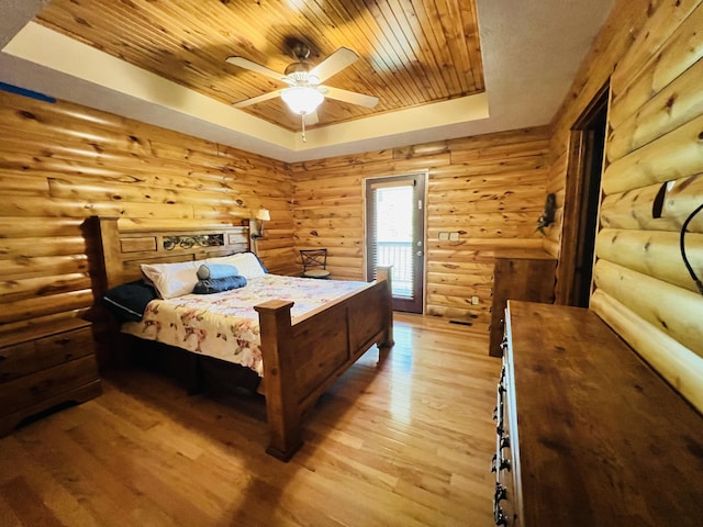 bedroom with rustic walls, a raised ceiling, a ceiling fan, wood ceiling, and light wood-style flooring