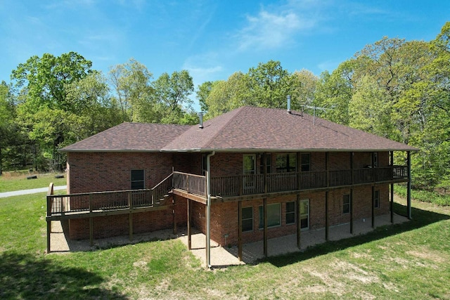 back of property with a patio area, a wooden deck, brick siding, and a yard