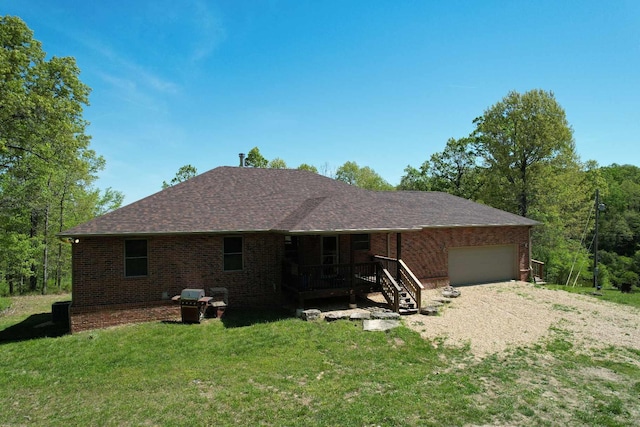 rear view of house featuring an attached garage, a porch, brick siding, and a yard
