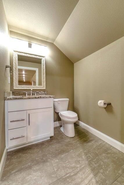 21942 Mill Creek Cir, Shell Knob, MO 65747 - half bath with vaulted ceiling, a textured ceiling, vanity, baseboards, and toilet