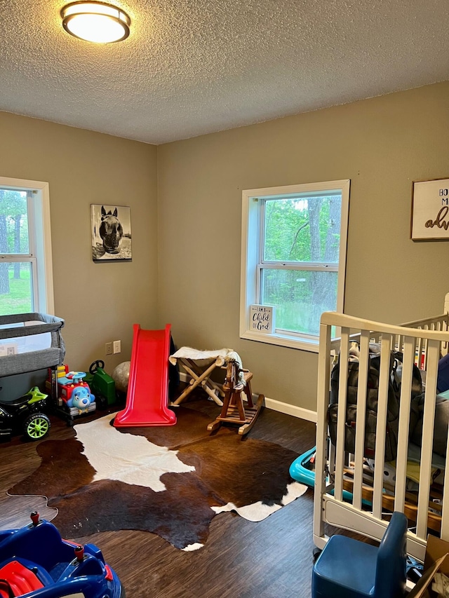 bedroom featuring a textured ceiling, wood finished floors, and baseboards