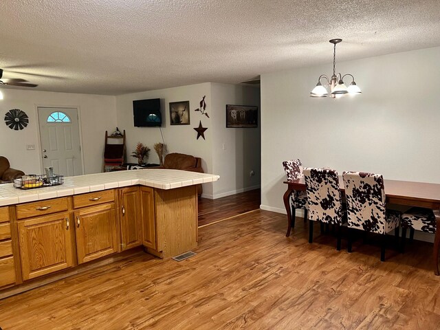 kitchen with light wood-style floors, open floor plan, visible vents, and tile countertops