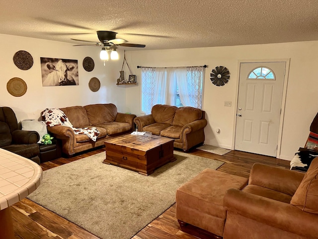 living room with a textured ceiling, dark wood-type flooring, plenty of natural light, and a ceiling fan