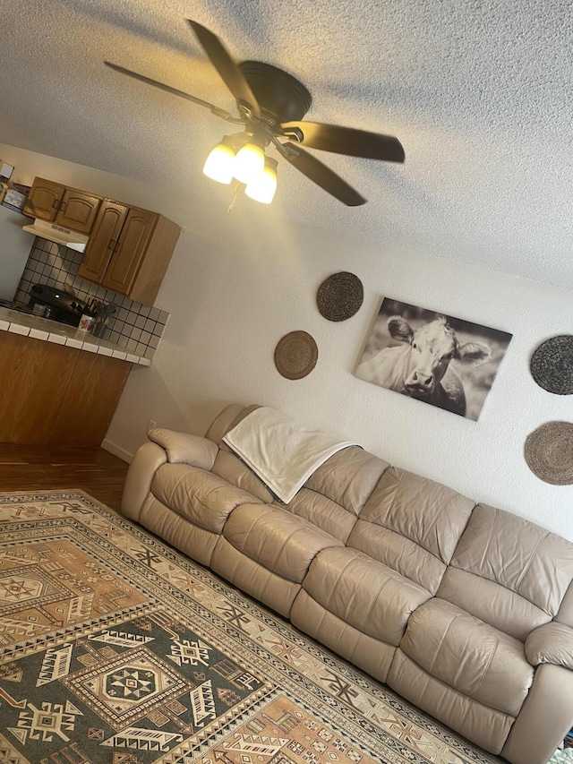 living room with a ceiling fan, a textured ceiling, and wood finished floors